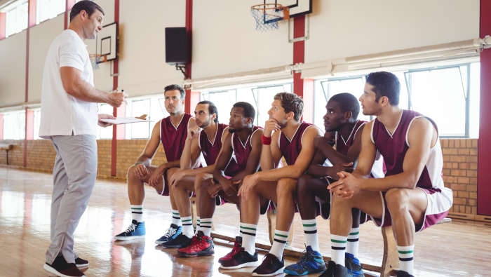 Ein Sportlehrer erklärt einer Basketball-Mannschaft die nächsten Spielzüge