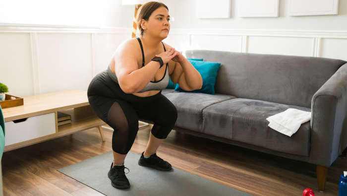 Krafttraining Übungen: übergewichtige Frau macht Kniebeugen