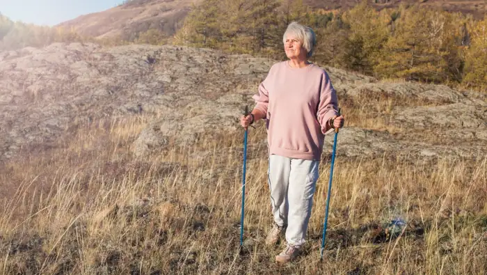 Eine ältere Frau macht Nordic Walking, um sich fit zu halten.