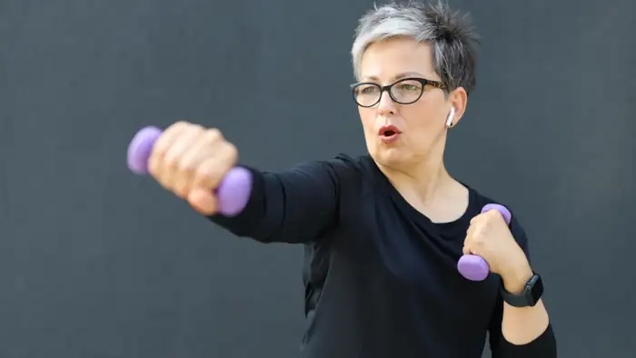 Eine Frau 50+ trainiert mit einem Paar Kurzhanteln